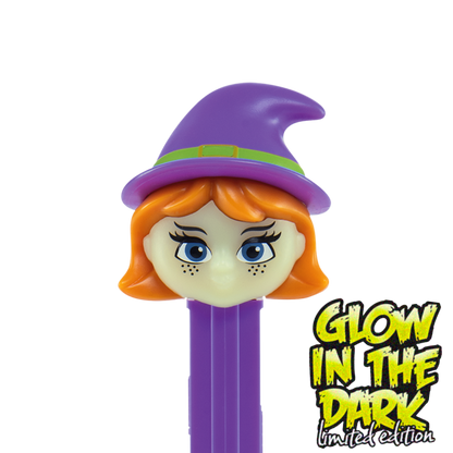 Detailansicht des PEZ-Spenders 'Hexe Glow in the Dark': Ein Hexenkopf mit violettem Spitzhut, orangefarbenen Haaren, blauen Augen und Sommersprossen auf einem violetten Spenderkörper.